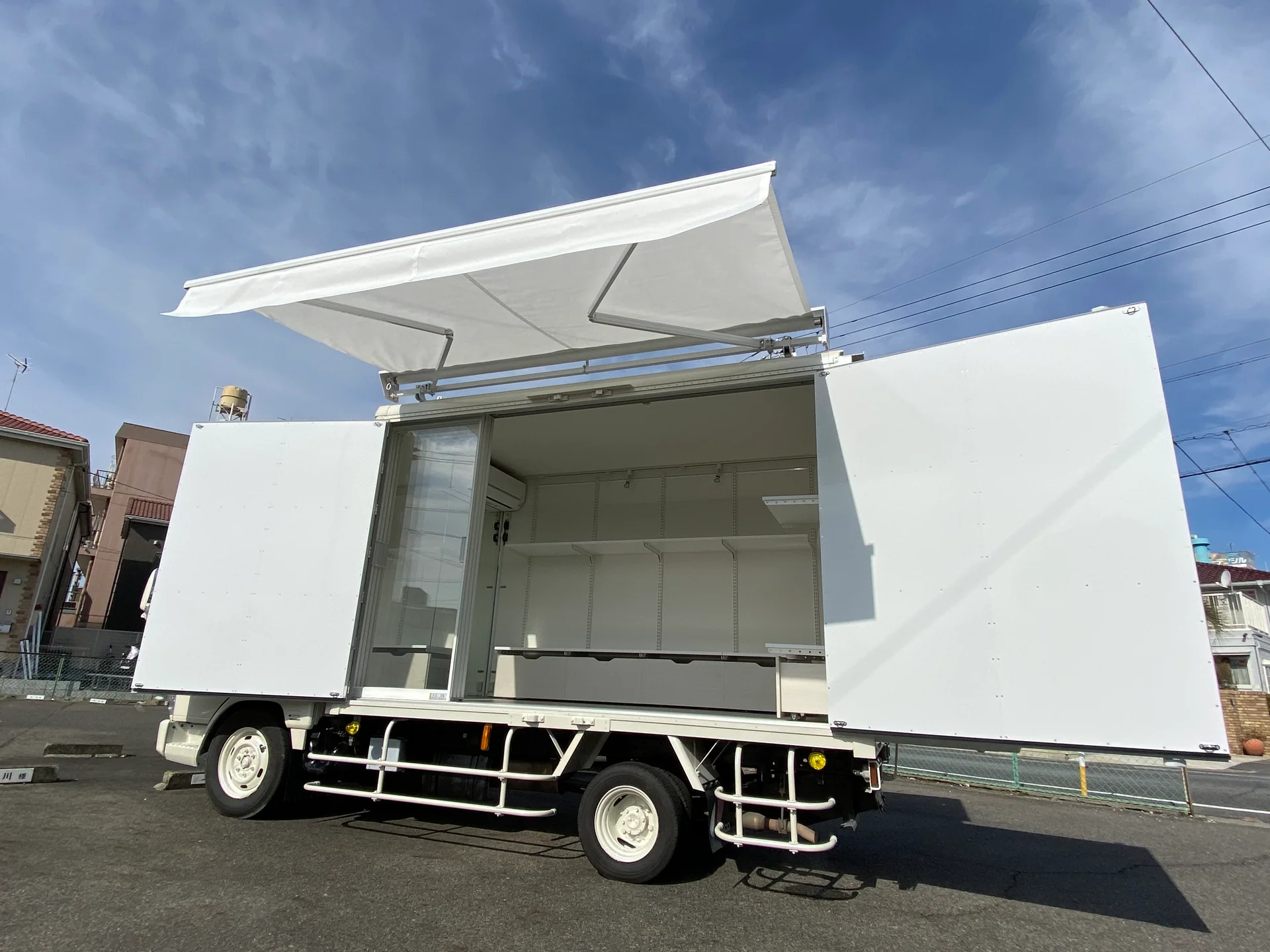 オーニングとガラス扉を備えた白い販売車両の完成例